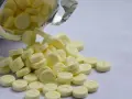 Żółte tabletki, niektóre z literą "D" lub cyfrą "5", wysypują się z białej butelki. To może być valium.