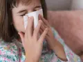 Dziewczynka z chusteczką przy nosie, być może potrzebuje antybiotyku na zatoki.