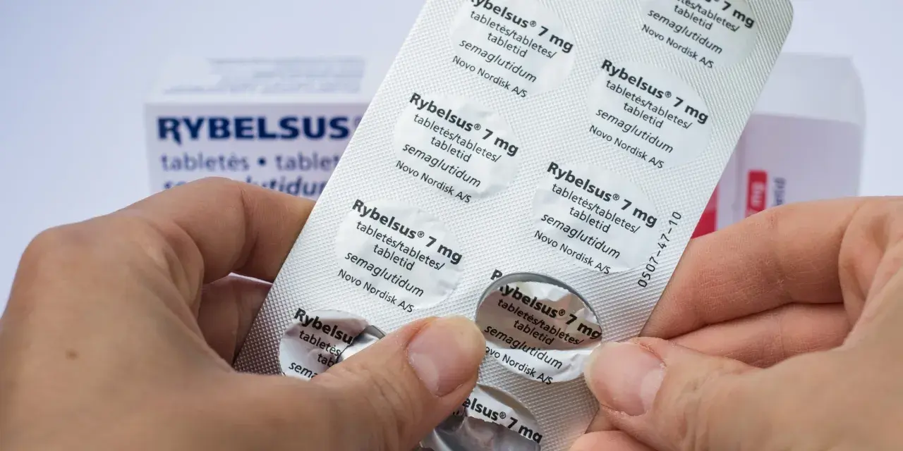 Dłonie trzymają opakowanie leku Rybelsus 7 mg. Cena Rybelsus jest ważnym czynnikiem dla pacjentów.