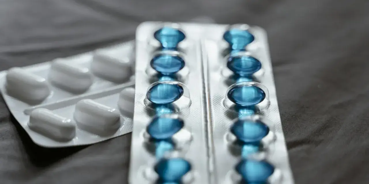 Dwa blistry leków: jeden z białymi kapsułkami, drugi z niebieskimi, które mogą być pregabalin accord.