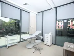Gabinet dermatologiczny z fotelem zabiegowym, szafką i wózkiem.