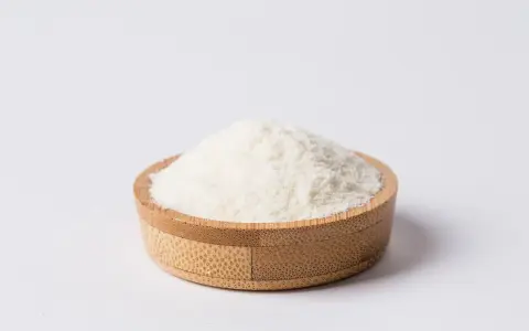 Biały proszek w drewnianej miseczce. To inulina, naturalny prebiotyk.