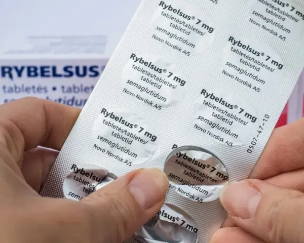 Dłonie trzymają opakowanie leku Rybelsus 7 mg. Cena Rybelsus jest ważnym czynnikiem dla pacjentów.