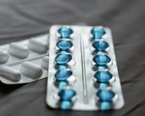 Dwa blistry leków: jeden z białymi kapsułkami, drugi z niebieskimi, które mogą być pregabalin accord.