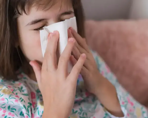Dziewczynka z chusteczką przy nosie, być może potrzebuje antybiotyku na zatoki.