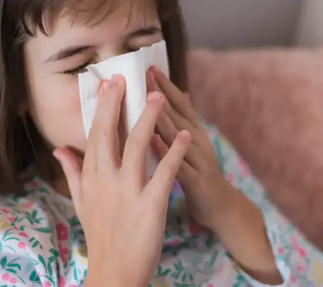 Dziewczynka z chusteczką przy nosie, być może potrzebuje antybiotyku na zatoki.