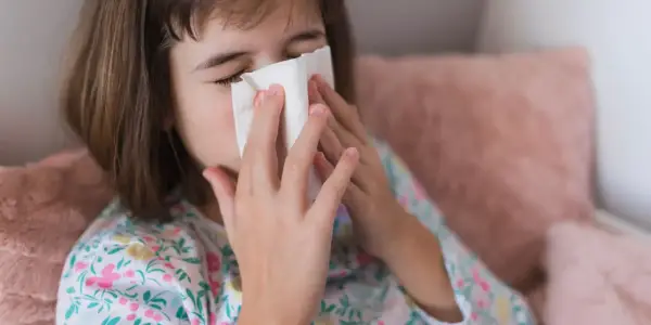 Dziewczynka z chusteczką przy nosie, być może potrzebuje antybiotyku na zatoki.