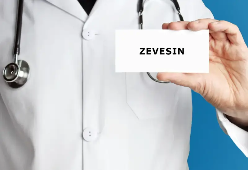 Lekarz w białym kitlu trzyma kartkę z napisem ZEVEISIN. Stetoskop wisi na jego szyi.